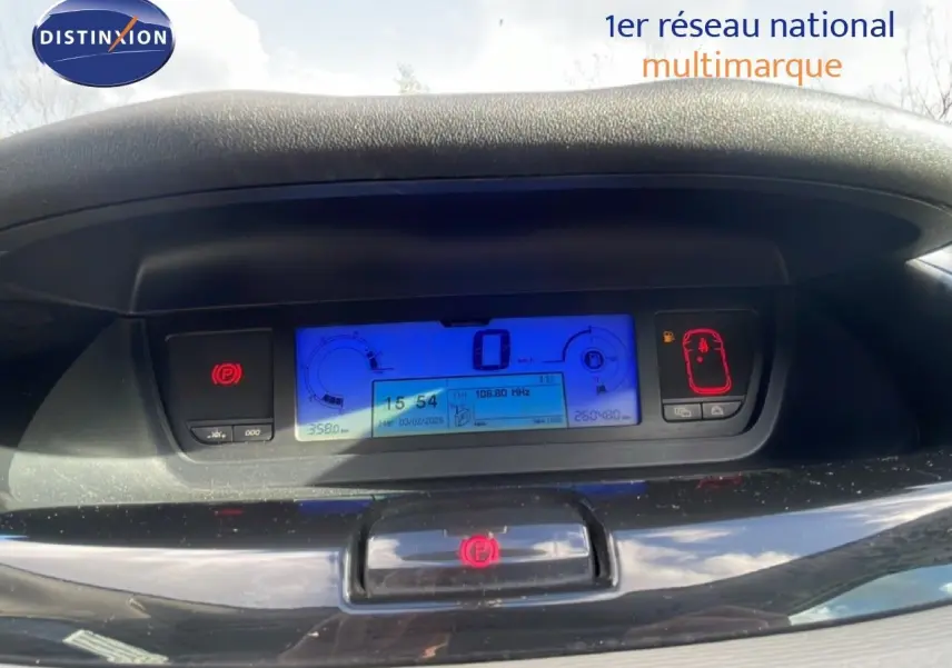 Tableau de bord numérique bleu de Citroën C4 Picasso noir métal 2008, affichant vitesse et alertes au centre.