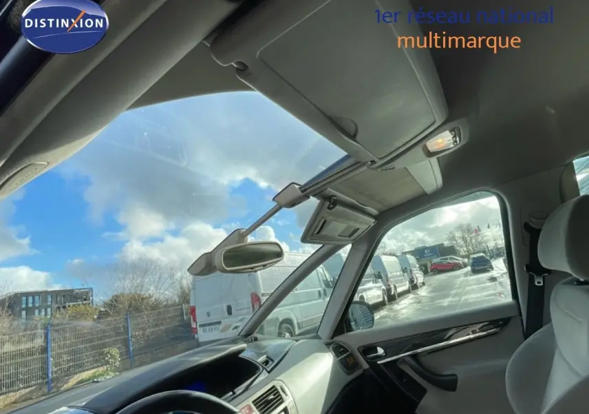 Vue intérieure côté conducteur de la Citroën C4 Picasso noire métal, montrant le tableau de bord et le toit panoramique.