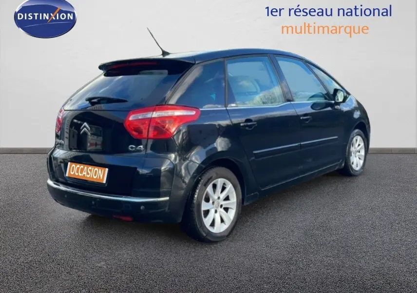 Vue 3/4 arrière droite d'une Citroën C4 Picasso noire métal de 2008 avec feux arrière rouges et jantes alliage argentées.