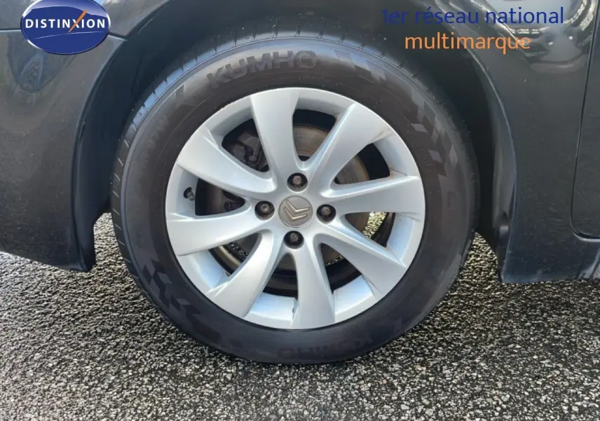 Gros plan sur la roue avant gauche d'une Citroën C4 Picasso noire métallisée avec jante alliage 16 pouces.