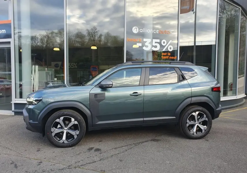 Profil droit du Dacia Duster 2026 vert cèdre avec jantes alliage 18” diamantées et barres de toit longitudinales.