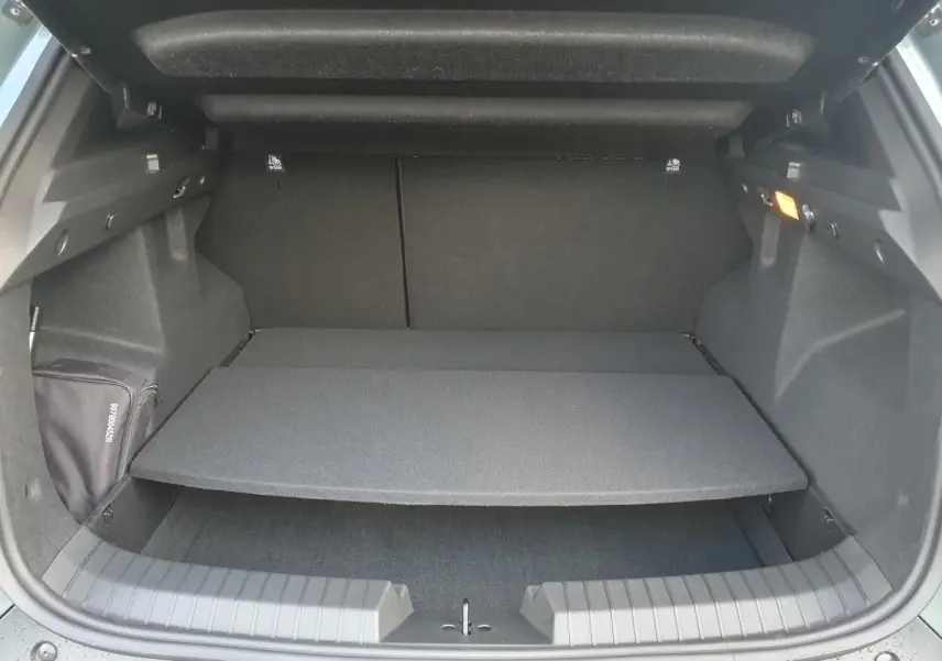 Coffre ouvert du Dacia Duster 2026, vue arrière, montrant la tablette de séparation et l'intérieur noir du coffre.