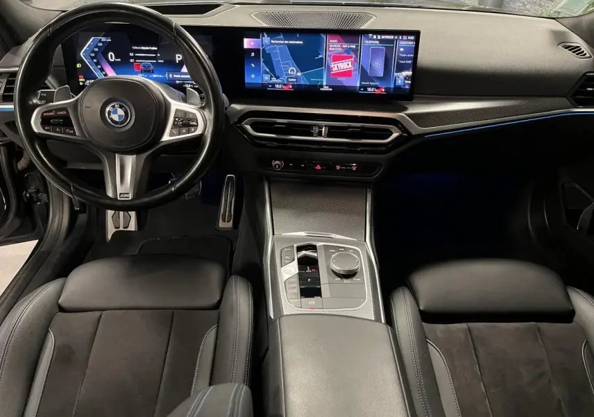 Vue intérieure avant de la BMW Série 3 G21 M Sport 320e noire, avec tableau de bord numérique et écran tactile large.