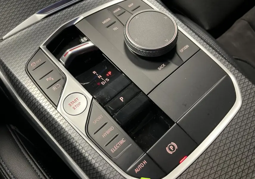 Gros plan sur la console centrale noire de la BMW Série 3 G21 M Sport avec sélecteur de mode hybride et bouton Start/Stop.