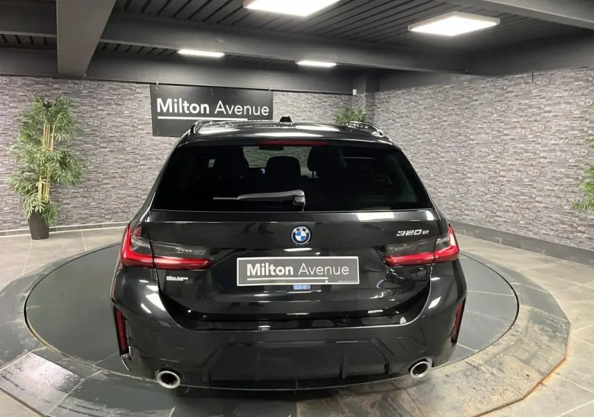 Vue arrière d'une BMW Série 3 320e Touring noire avec double sortie d'échappement et feux arrière LED.