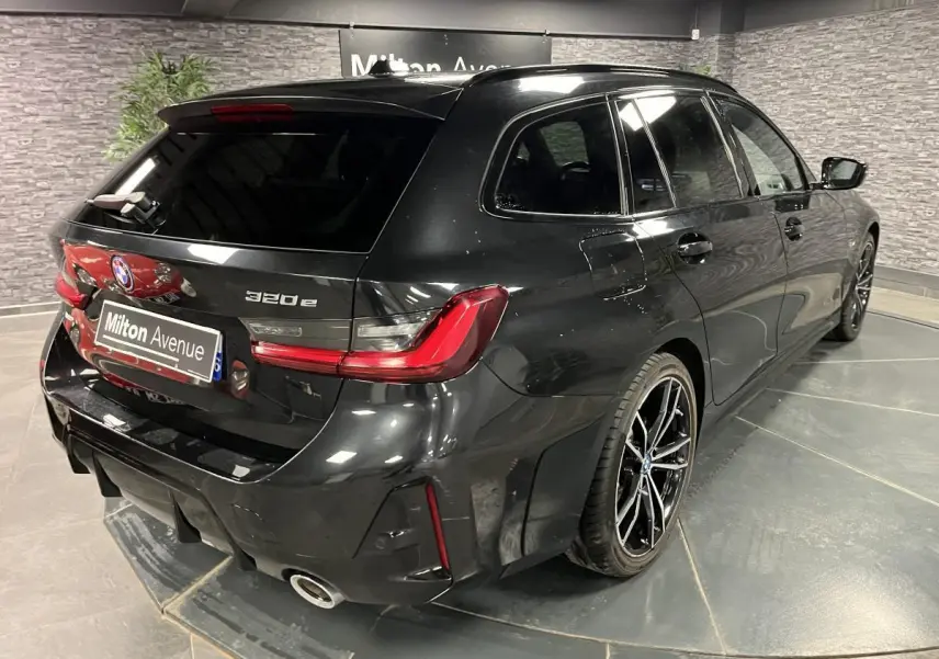 BMW Série 3 320e Touring noire vue en 3/4 arrière droit, avec jantes M Sport bicolores et feux LED distinctifs.