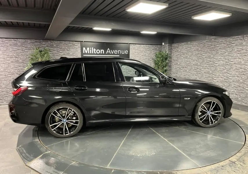 BMW Série 3 320e Touring noire vue de profil côté gauche, avec jantes 19 pouces bicolores et toit ouvrant panoramique.