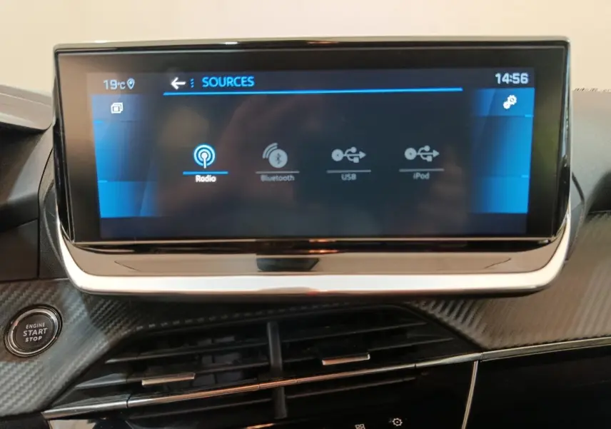 Écran tactile central 10 pouces de la Peugeot 208 PureTech 100, avec bouton démarrage et finition carbone noire.