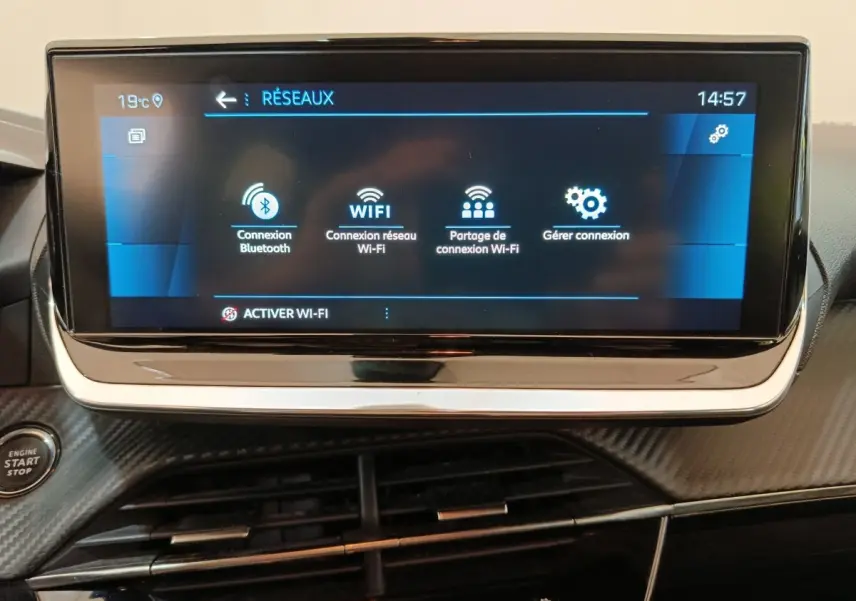 Vue rapprochée de l'écran tactile central affichant les options de connexion réseau dans l'habitacle noir d'une Peugeot 208 blanche.
