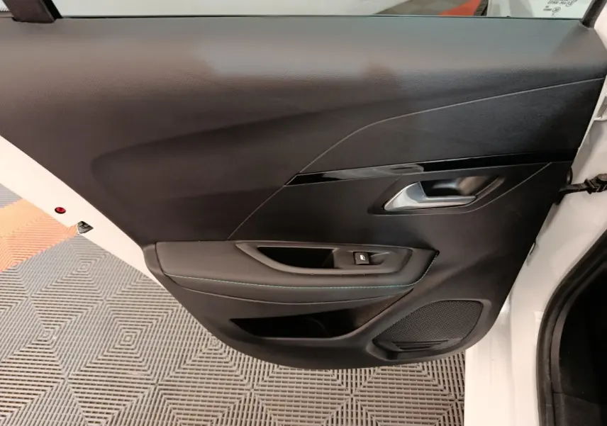 Vue rapprochée de la porte arrière droite noire avec poignée argentée d'une Peugeot 208 blanche 2021.