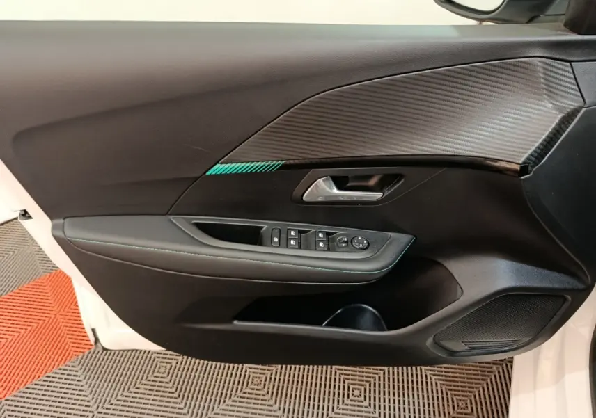 Vue intérieure côté gauche de la porte avant blanche du Peugeot 208 avec garniture noire et insert effet carbone.