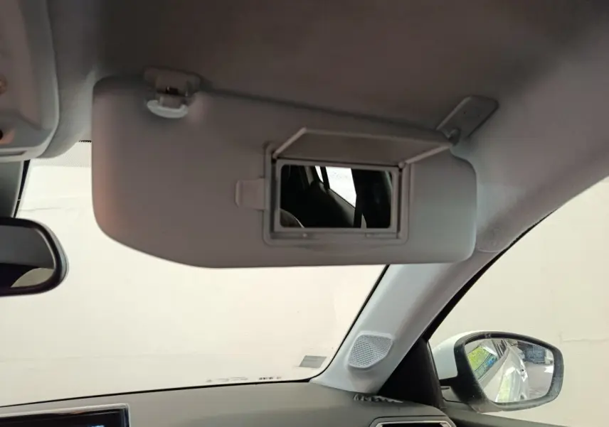 Intérieur de la Peugeot 208 blanc, vue sur le pare-soleil avec miroir et rétroviseur côté droit visible.