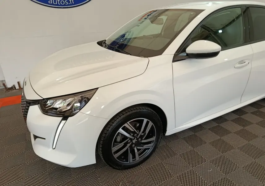 Vue 3/4 avant droit d’une Peugeot 208 blanche avec phares LED et jantes alliage noires.