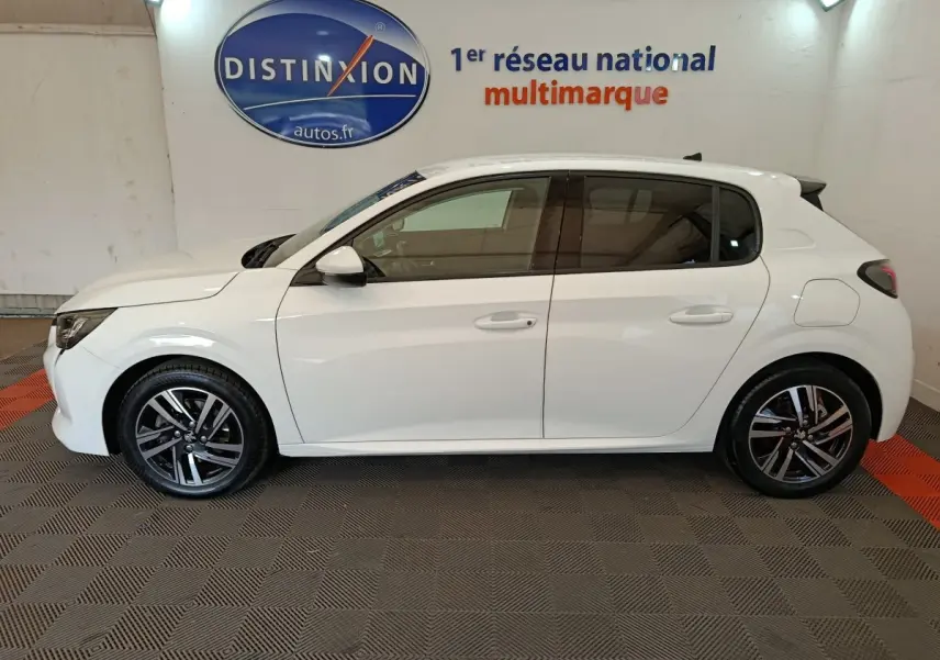 Peugeot 208 blanc vue de profil côté gauche, avec jantes alliage et vitres teintées, en intérieur showroom.