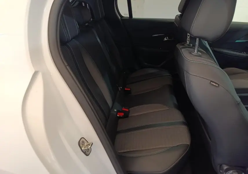 Vue intérieure côté gauche sur la banquette arrière noire de la Peugeot 208 blanche PureTech 100 S&S Allure Business.