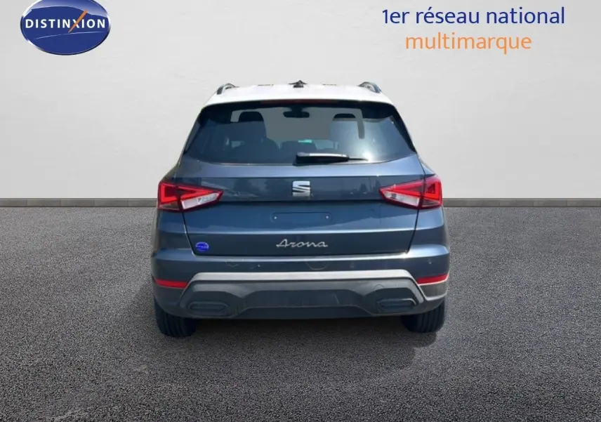 Vue arrière d'un SEAT Arona gris Magnetic avec toit blanc, feux arrière allumés, sur fond neutre.