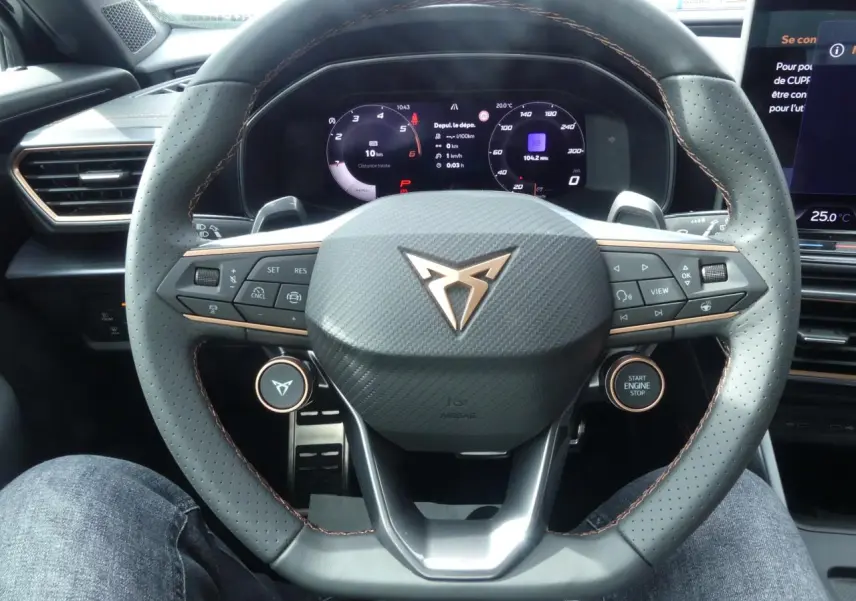 Vue rapprochée du volant perforé noir avec surpiqûres cuivrées et tableau de bord digital du CUPRA Formentor gris magnétique 2025.