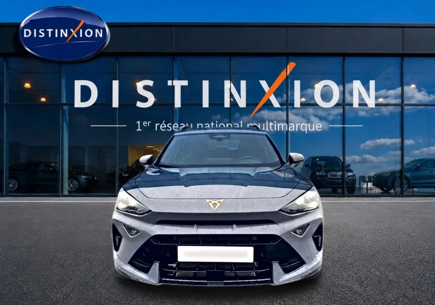 Vue frontale d'un CUPRA Formentor gris graphene 2026 avec logo distinctif sur calandre, devant showroom Distinxion.