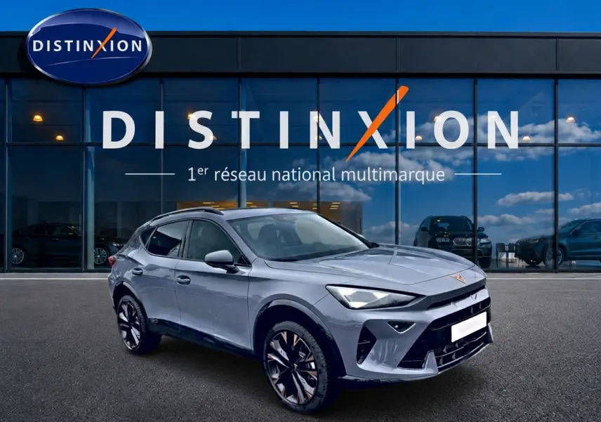 Vue 3/4 avant d'un CUPRA Formentor gris graphene avec jantes noires et détails cuivrés, devant une vitrine Distinxion.