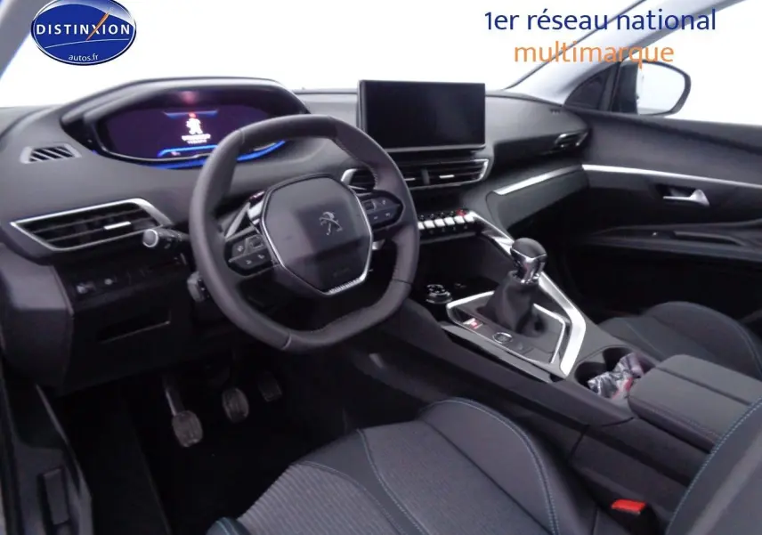 Intérieur du Peugeot 3008 2023 vu côté conducteur, avec volant compact et sellerie noire aux surpiqûres bleues.