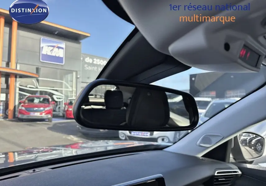 Vue intérieure du tableau de bord et rétroviseur central d'une Peugeot 2008 gris Artense, avec reflet du siège arrière visible.