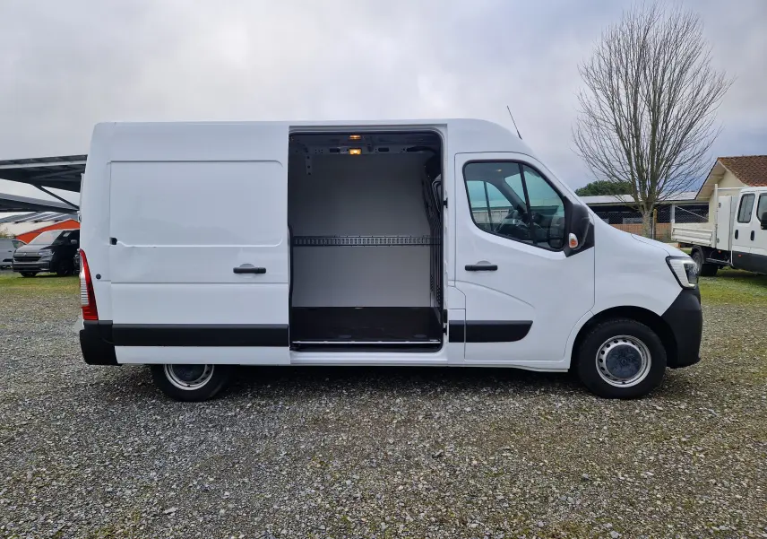 Vue latérale droite d'un Renault Master blanc 2023 avec porte coulissante ouverte dévoilant l'intérieur vide du fourgon.