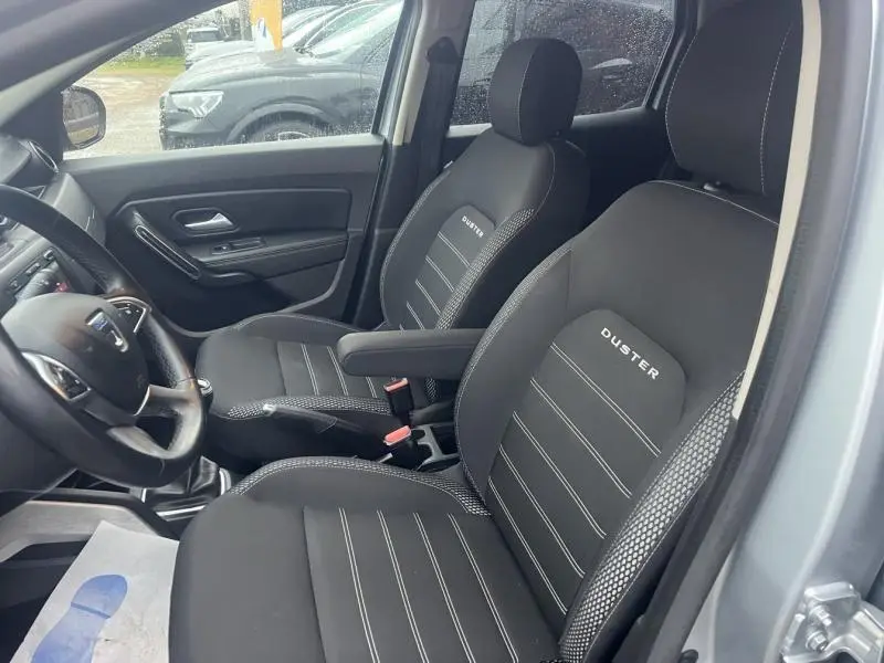 Vue intérieure côté gauche du Dacia Duster 2021, sièges noirs avec logo Duster et accoudoir central visible