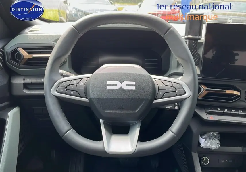 Vue centrée sur le volant multifonction du Dacia Duster 2025 avec tableau de bord et écran tactile visibles.