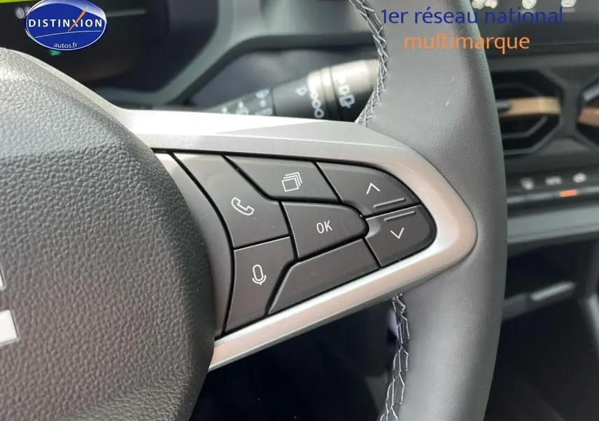 Gros plan sur les commandes au volant côté droit du Dacia Duster noir 2025, avec tableau de bord en arrière-plan.