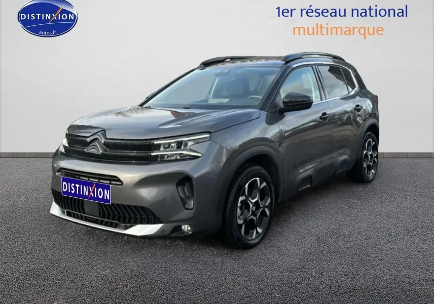 Citroën C5 Aircross gris métallisé vue 3/4 avant droit avec jantes alu et barres de toit noires.