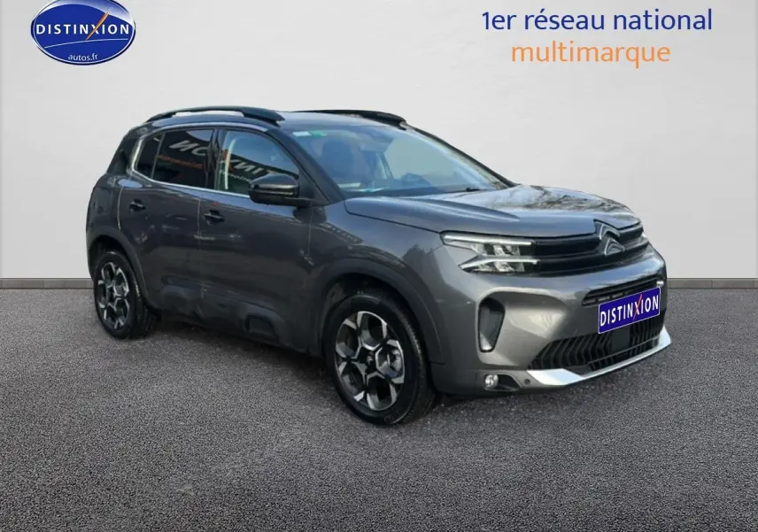 Citroën C5 Aircross gris 3/4 avant droit avec jantes alu et barres de toit visibles sur fond neutre.