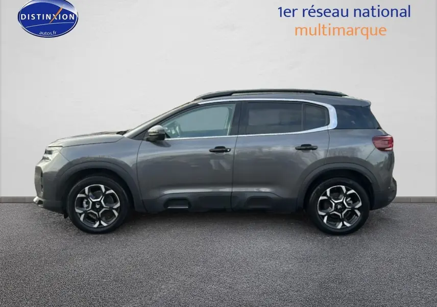 Vue latérale droite d'un Citroën C5 Aircross gris métallisé avec jantes alliage et barres de toit noires.