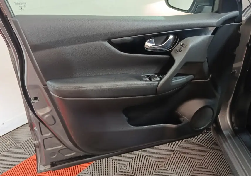Vue rapprochée de la porte avant gauche noire du Nissan Qashqai gris clair, montrant la poignée et les commandes de vitres.