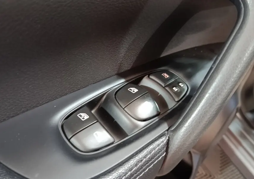 Gros plan sur les commandes de lève-vitres et verrouillage sur la porte côté conducteur du Nissan Qashqai gris clair 2019.