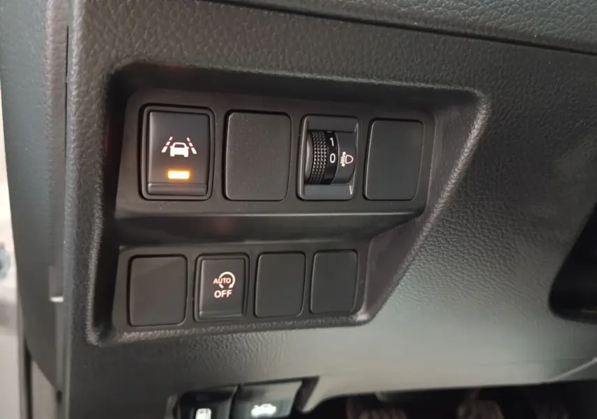 Gros plan sur les commandes du tableau de bord du Nissan Qashqai gris clair, avec boutons d’aide à la conduite allumés.