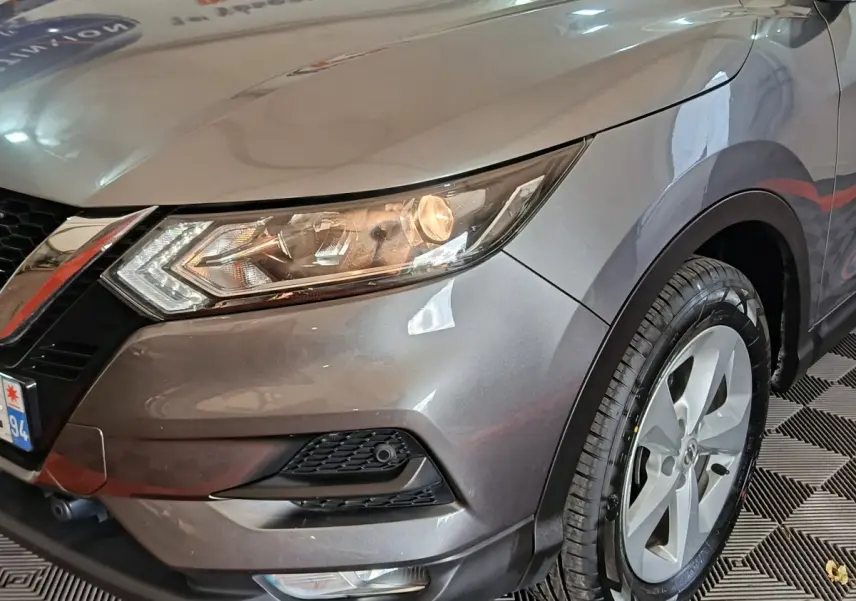 Vue 3/4 avant droit d'un Nissan Qashqai gris clair mettant en valeur le phare avant et la jante alliage.