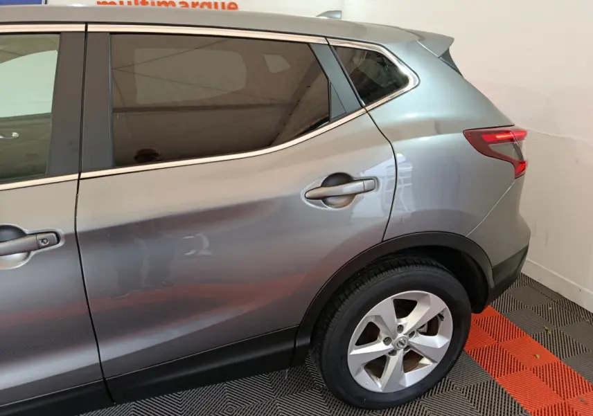 Vue côté droit arrière du Nissan Qashqai gris clair 2019 avec jante alliage et feux arrière LED allumés.