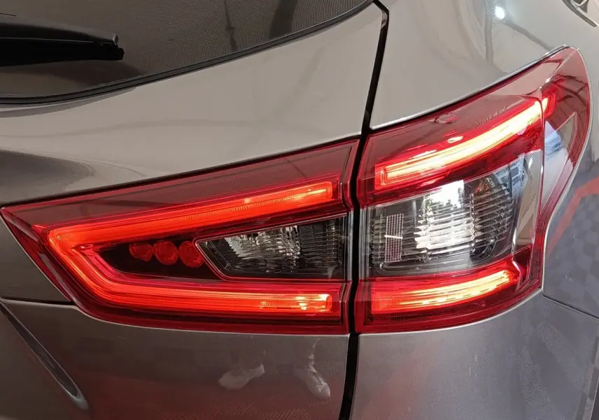 Gros plan sur le feu arrière droit rouge et blanc d’un Nissan Qashqai gris clair, version 2019.