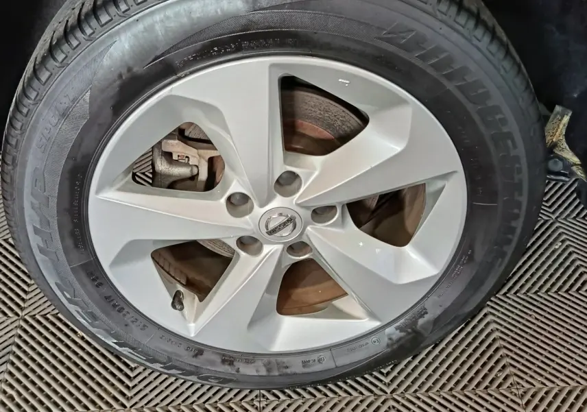 Gros plan sur la roue avant droite du Nissan Qashqai gris clair, jante alliage à cinq branches, pneu Bridgestone.
