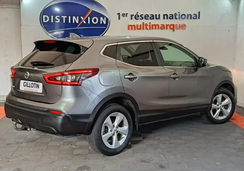 Vue 3/4 arrière droit d'un Nissan Qashqai gris clair garé en intérieur avec jantes alliage et feux arrière allongés.