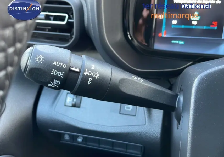 Gros plan sur la commande des phares à gauche du volant dans l'habitacle du Citroën Berlingo blanc glacier 2025.