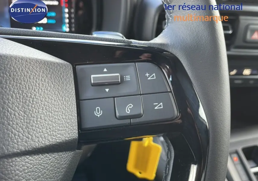 Gros plan sur les commandes du volant côté gauche du Citroën Berlingo blanc glacier, avec boutons de volume et téléphone.