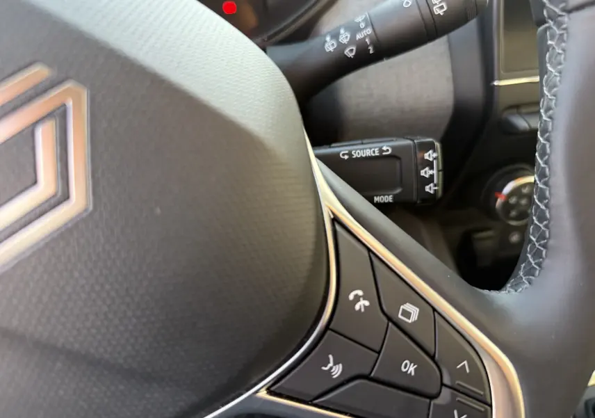 Gros plan sur le volant noir de la Renault Clio V avec commandes intégrées et commandes au volant visibles.