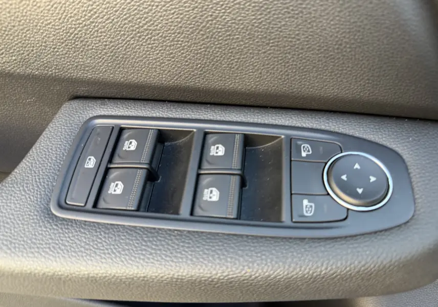 Panneau de commandes des vitres et rétroviseurs côté conducteur dans une Renault Clio V, finition tissu noir.