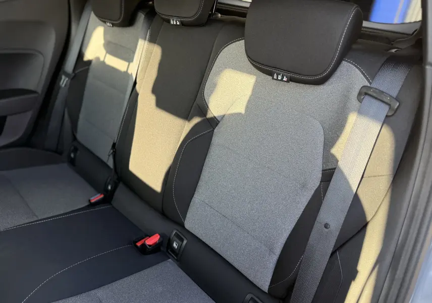 Vue rapprochée des sièges arrière gris clair et noir de la Renault Clio V 2025, avec ceinture de sécurité visible à droite.
