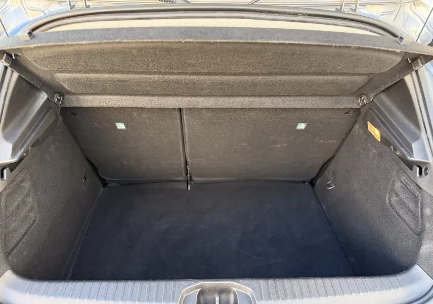 Coffre ouvert de la Renault Clio V gris schiste métal, montrant un espace de rangement propre et vide, vue arrière.