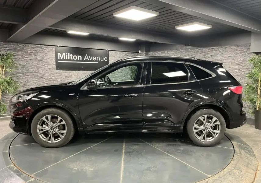Vue latérale gauche d'un Ford Kuga noir 2022 avec jantes alliage 18 pouces et vitres arrière surteintées.