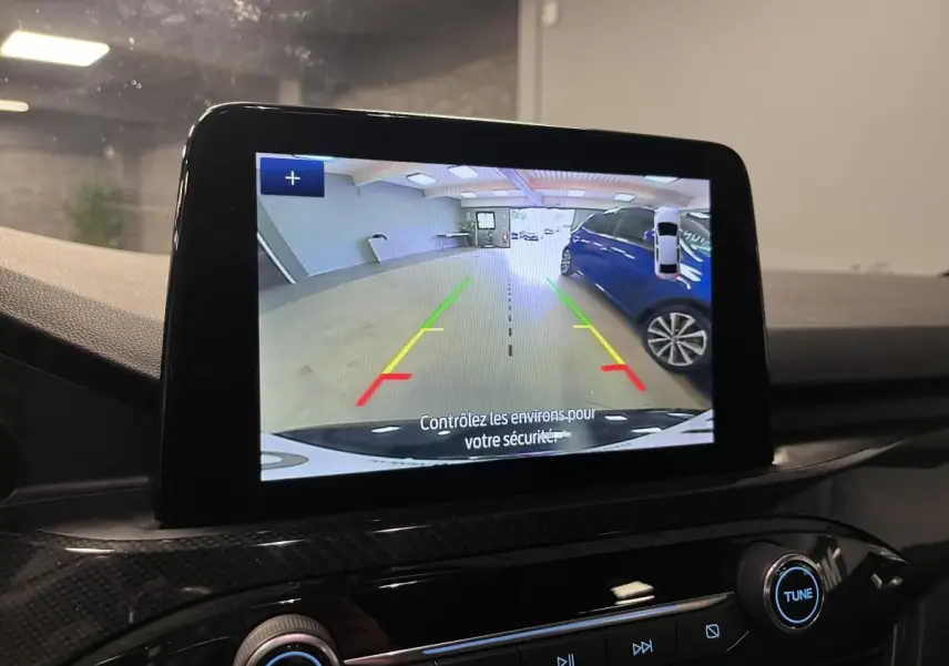 Écran central montrant la caméra de recul du Ford Kuga noir, avec vue arrière sur un parking intérieur.