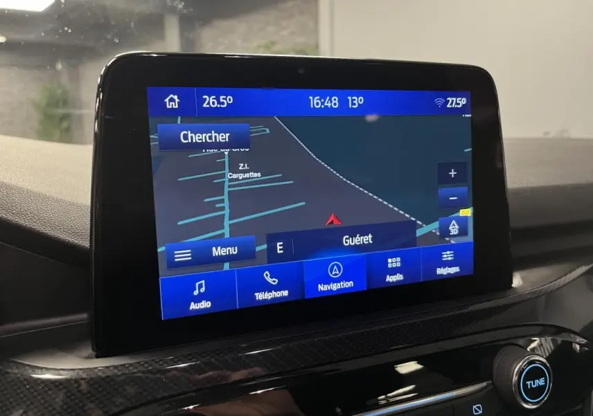 Écran tactile central du Ford Kuga 2022 affichant la navigation avec interface bleue et commandes audio visibles.