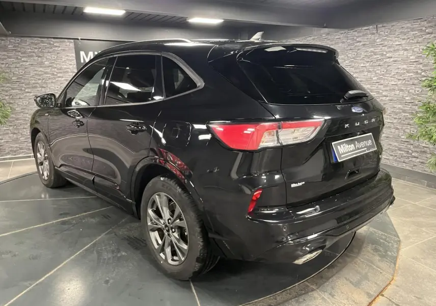 Vue 3/4 arrière droite d'un Ford Kuga noir avec jantes alliage 18 pouces et badges ST-Line visibles.